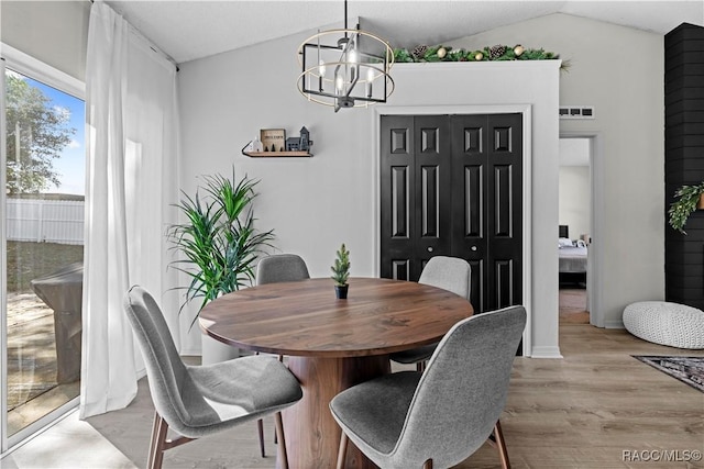 dining room with light wood-type flooring, lofted ceiling, and a chandelier