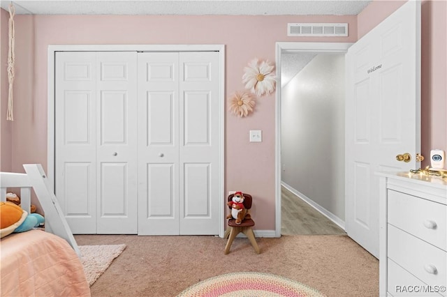 carpeted bedroom featuring a textured ceiling and a closet