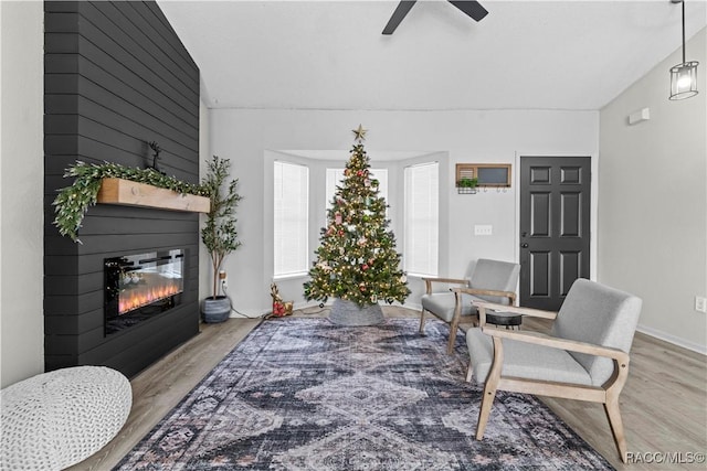 living room with ceiling fan, light hardwood / wood-style flooring, and vaulted ceiling