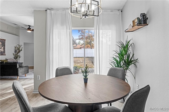 dining space featuring wood-type flooring and ceiling fan with notable chandelier