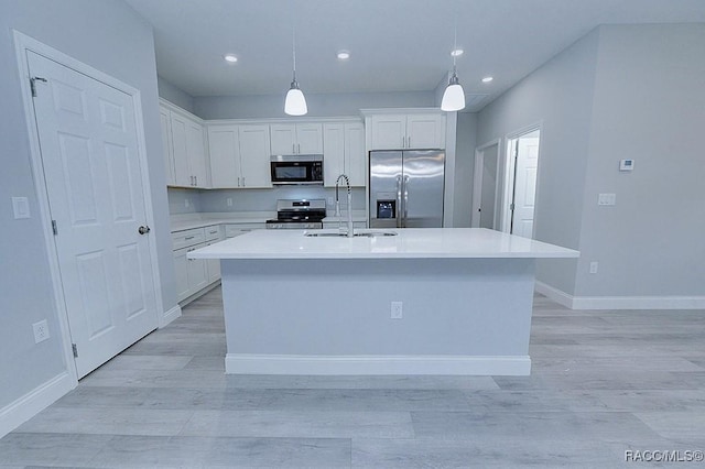 kitchen featuring white cabinets, pendant lighting, sink, and appliances with stainless steel finishes