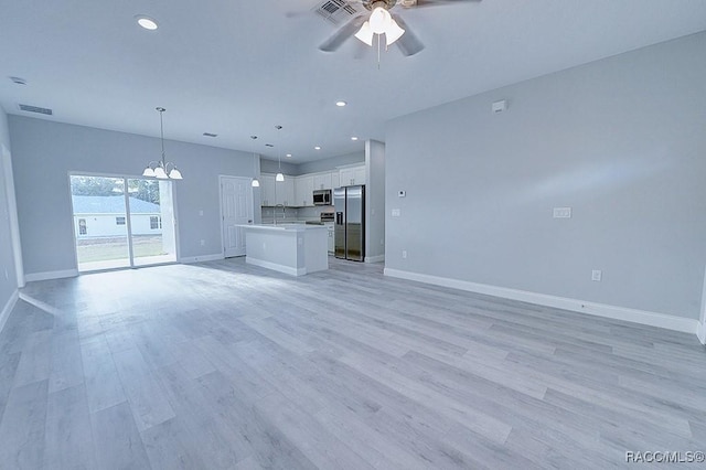 unfurnished living room featuring ceiling fan with notable chandelier, light wood-type flooring, and sink