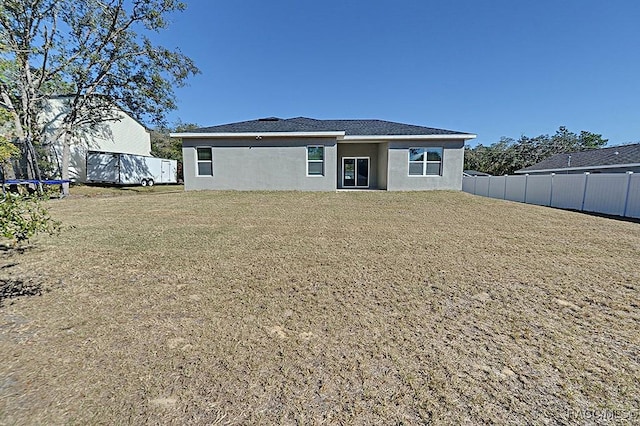 back of house with a yard and a trampoline