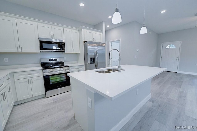 kitchen with appliances with stainless steel finishes, decorative light fixtures, white cabinetry, and a kitchen island with sink