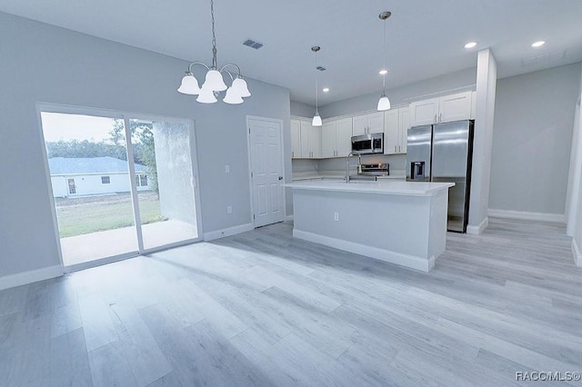 kitchen with sink, stainless steel appliances, pendant lighting, white cabinets, and light wood-type flooring