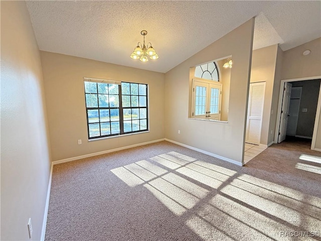 carpeted empty room featuring vaulted ceiling, a textured ceiling, and a notable chandelier