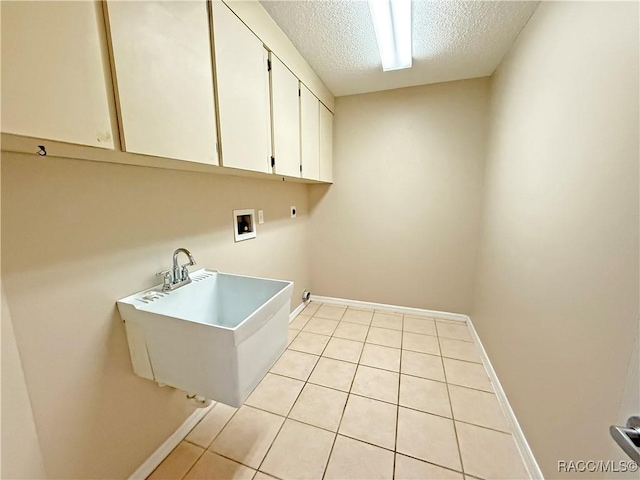 laundry room with sink, cabinets, a textured ceiling, light tile patterned floors, and hookup for a washing machine