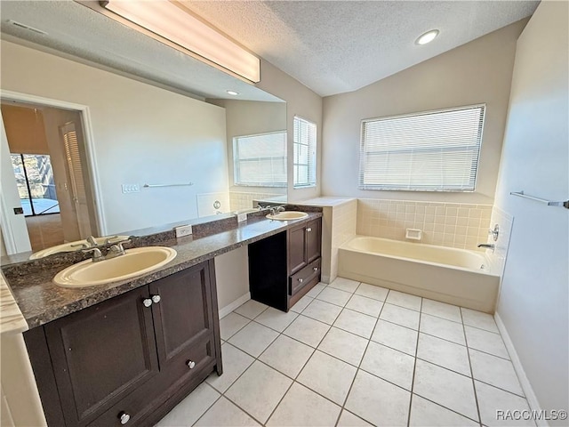 bathroom featuring a washtub, lofted ceiling, tile patterned flooring, vanity, and a textured ceiling