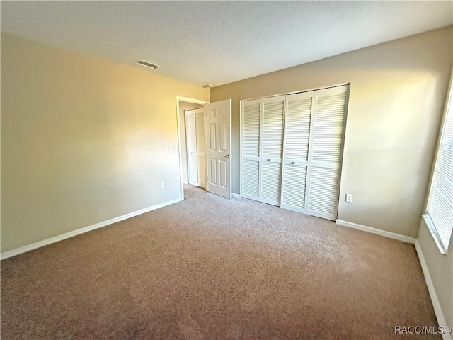 unfurnished bedroom with carpet flooring, a closet, and a textured ceiling