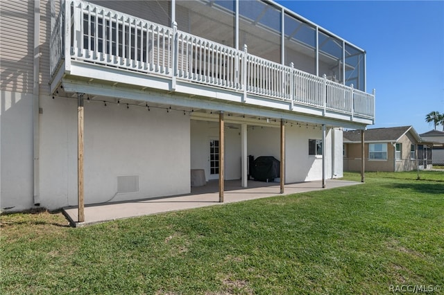 back of property featuring a yard, a patio, and glass enclosure