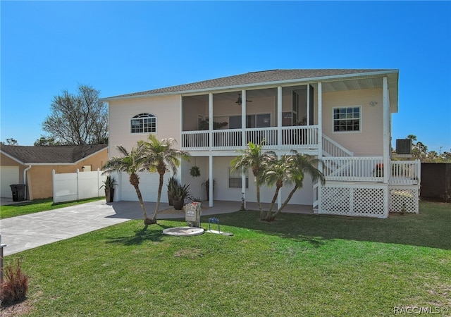 view of front of home featuring a sunroom, cooling unit, a front yard, and a garage