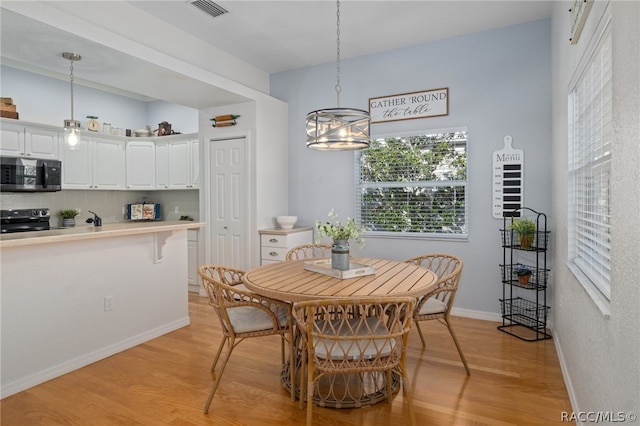 dining area with a notable chandelier, light wood-type flooring, and sink