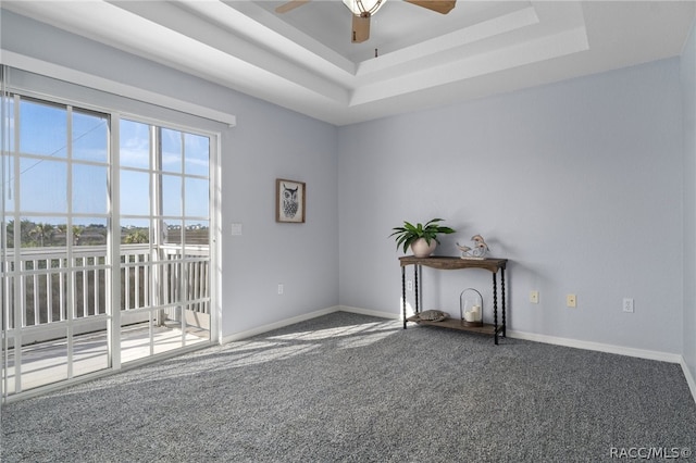 carpeted empty room featuring a raised ceiling and ceiling fan