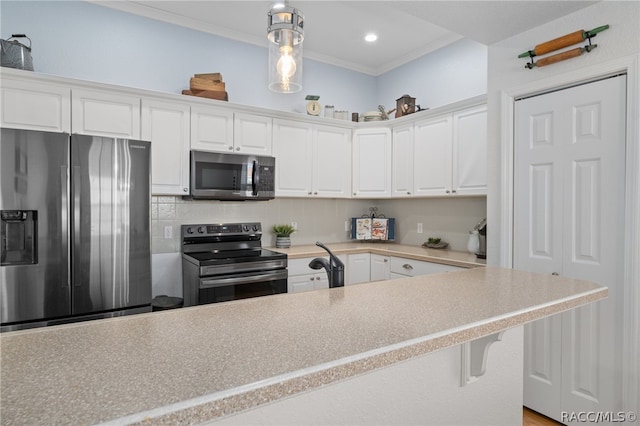 kitchen featuring white cabinets, ornamental molding, appliances with stainless steel finishes, decorative light fixtures, and a breakfast bar area