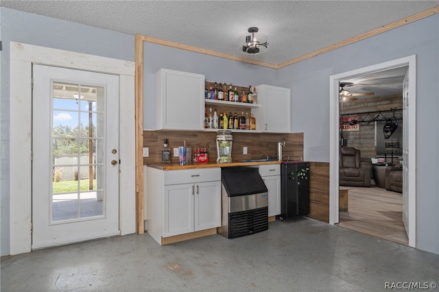 bar with a textured ceiling, white cabinetry, and ceiling fan