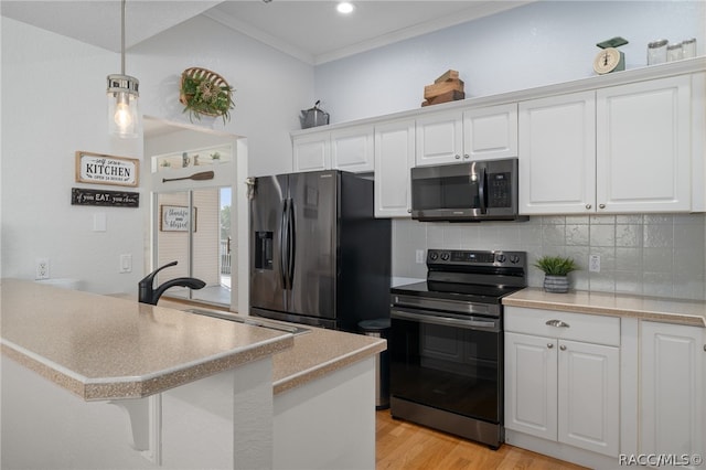 kitchen featuring white cabinets, decorative light fixtures, crown molding, and appliances with stainless steel finishes