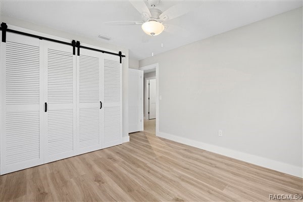 3929 N Sagomon Pt, Crystal River, FL 34428 - unfurnished bedroom with a barn door, wood finished floors, a closet, and a ceiling fan