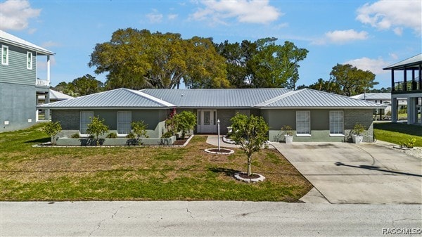 3929 N Sagomon Pt, Crystal River, FL 34428 - view of front of home featuring concrete driveway, a metal roof, and a front lawn