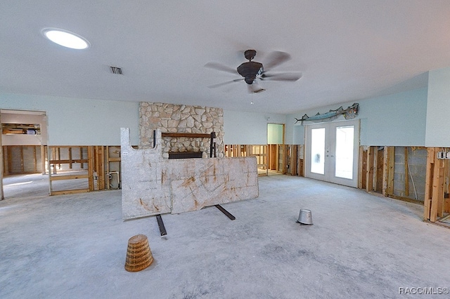 unfurnished living room featuring ceiling fan, light colored carpet, a fireplace, and french doors