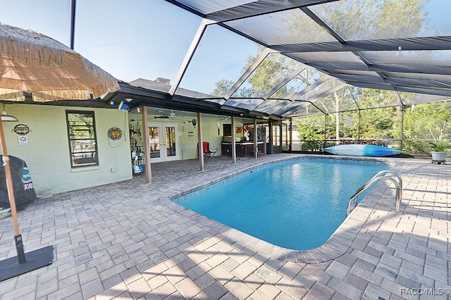 view of swimming pool with ceiling fan, a patio area, glass enclosure, and french doors