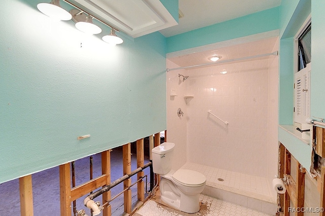 bathroom featuring a tile shower, toilet, and tile patterned floors