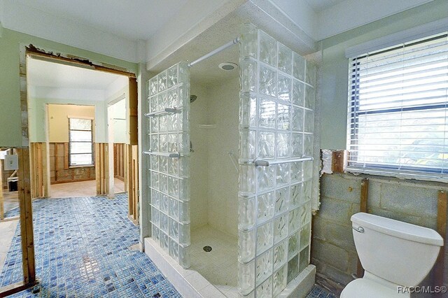 bathroom with a shower, tile patterned flooring, a healthy amount of sunlight, and toilet