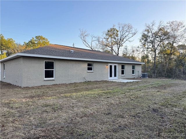 back of house featuring a lawn, roof with shingles, central air condition unit, a patio area, and stucco siding