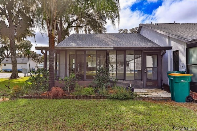 rear view of property featuring a lawn and a sunroom