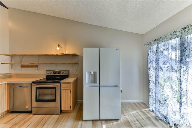 kitchen with appliances with stainless steel finishes, light wood-type flooring, a textured ceiling, and vaulted ceiling