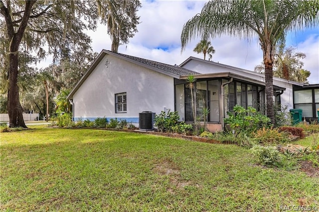 view of front of property with central AC unit, a sunroom, and a front yard