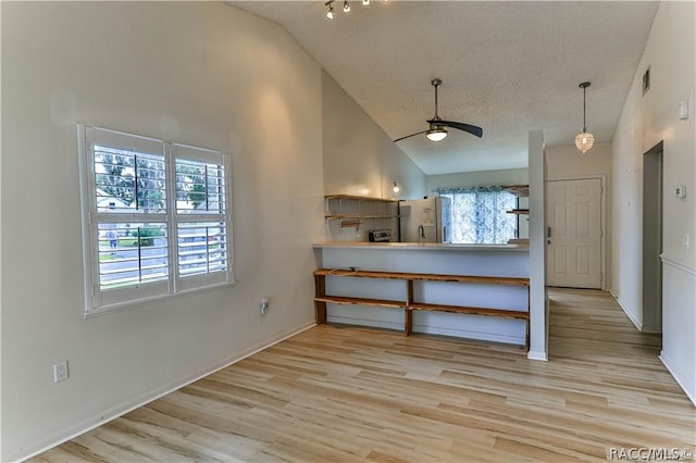 kitchen with ceiling fan, kitchen peninsula, high vaulted ceiling, and light hardwood / wood-style flooring