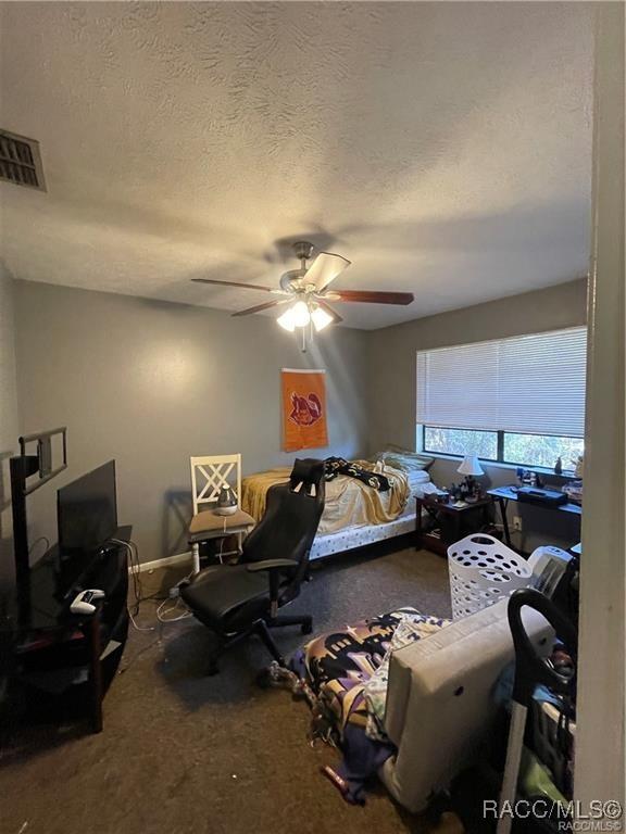 9445 W Milwaukee Ct, Crystal River, FL 34428 - carpeted bedroom featuring a textured ceiling and a ceiling fan