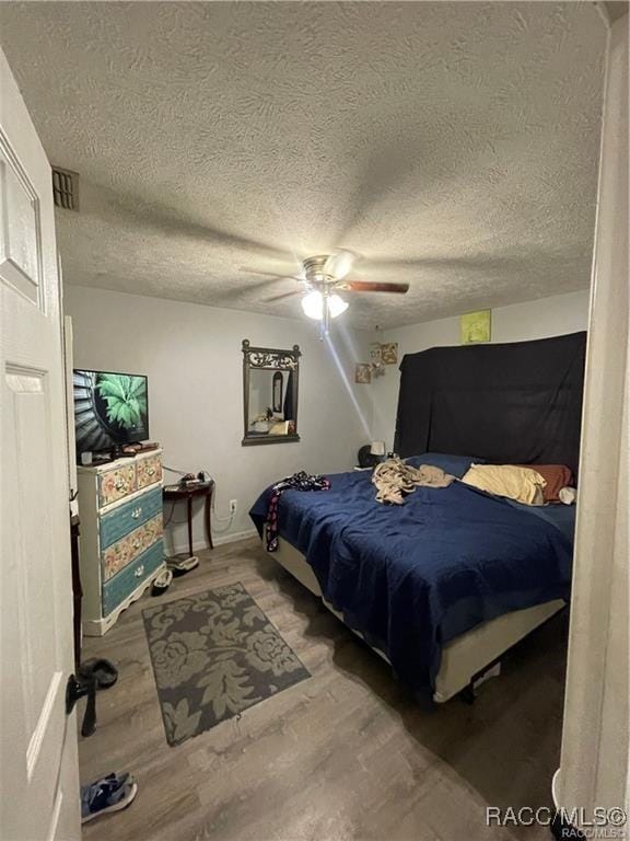 9445 W Milwaukee Ct, Crystal River, FL 34428 - bedroom featuring wood finished floors, a textured ceiling, and ceiling fan