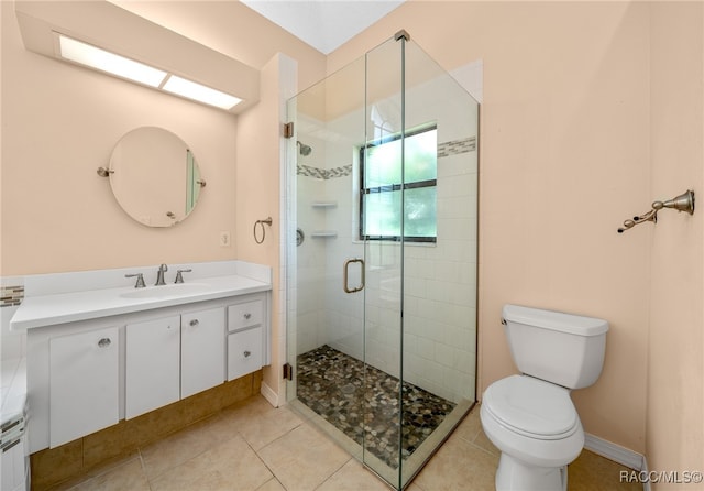 bathroom featuring tile patterned flooring, vanity, a shower with door, and toilet