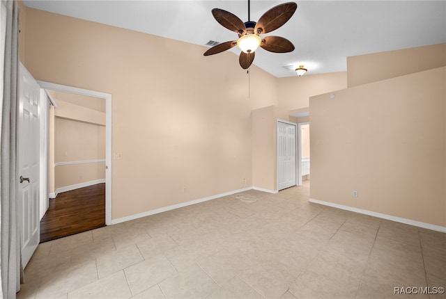 spare room with light tile patterned floors, high vaulted ceiling, and ceiling fan