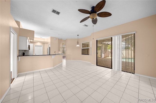 unfurnished living room with a textured ceiling, sink, ceiling fan, and light tile patterned flooring