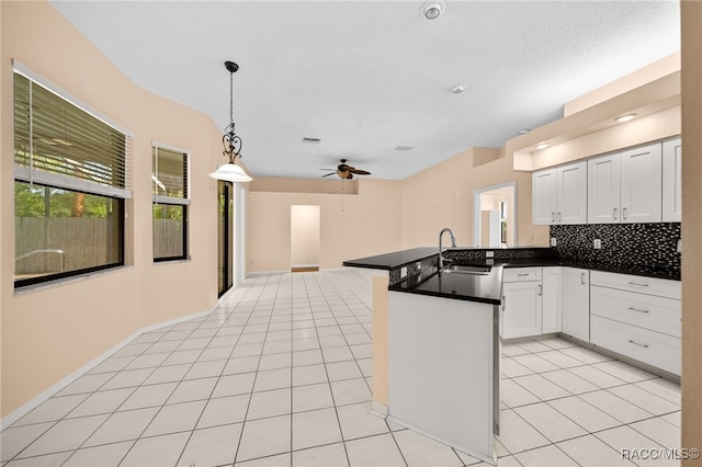 kitchen with ceiling fan, sink, kitchen peninsula, decorative light fixtures, and white cabinets