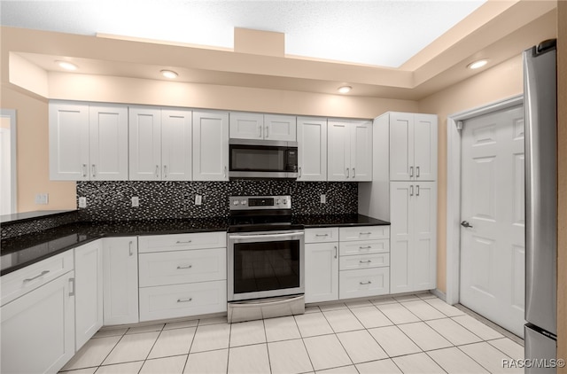 kitchen featuring tasteful backsplash, white cabinets, light tile patterned floors, and appliances with stainless steel finishes