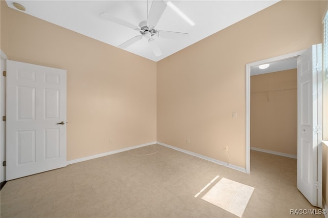 unfurnished bedroom featuring ceiling fan, light tile patterned flooring, a walk in closet, and a closet