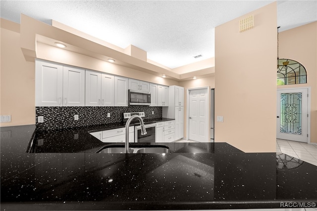 kitchen featuring dark stone countertops, white cabinetry, stainless steel appliances, and light tile patterned floors