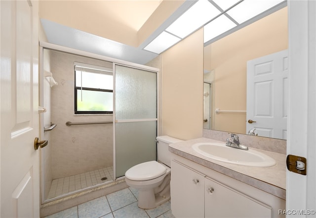 bathroom featuring tile patterned flooring, vanity, toilet, and walk in shower