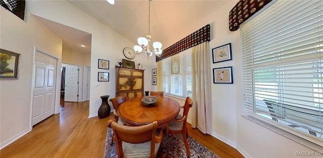 dining area featuring an inviting chandelier, vaulted ceiling, and light wood-type flooring