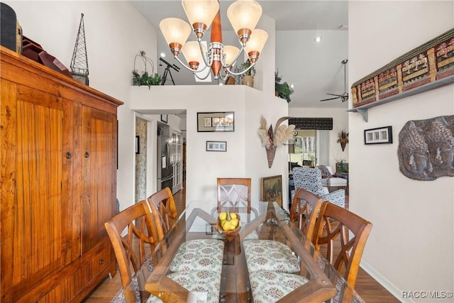 dining room with hardwood / wood-style flooring, a towering ceiling, and ceiling fan with notable chandelier