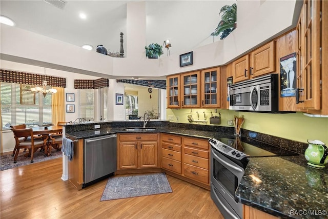 kitchen with sink, decorative light fixtures, dark stone counters, and appliances with stainless steel finishes