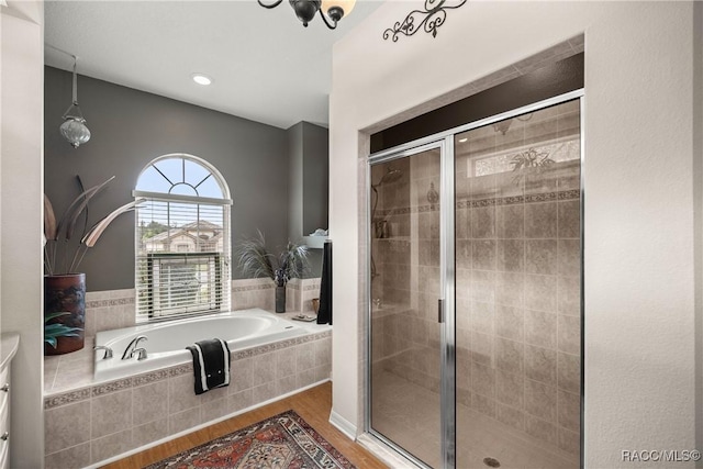 bathroom with hardwood / wood-style floors and shower with separate bathtub