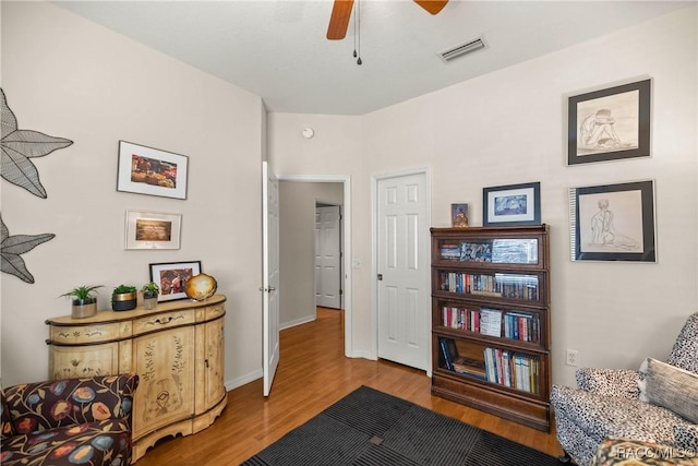 living area with hardwood / wood-style floors and ceiling fan