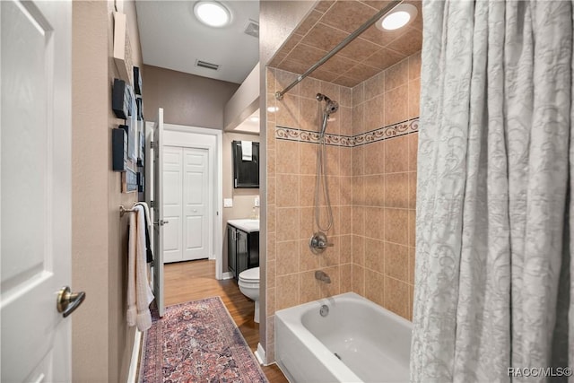 full bathroom featuring hardwood / wood-style flooring, vanity, shower / bath combination with curtain, and toilet