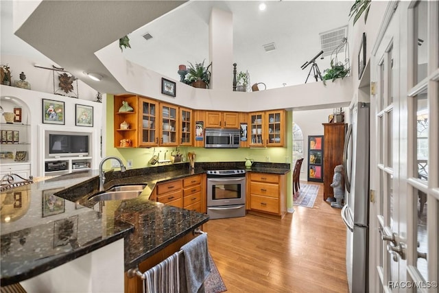 kitchen featuring stainless steel appliances, sink, dark stone counters, and kitchen peninsula