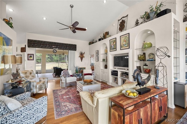 living room with ceiling fan, high vaulted ceiling, light hardwood / wood-style floors, and built in shelves