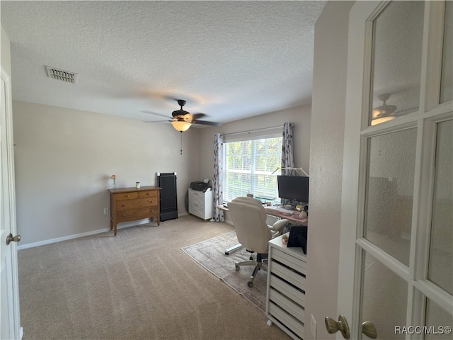 home office featuring carpet flooring, ceiling fan, a textured ceiling, baseboards, and visible vents